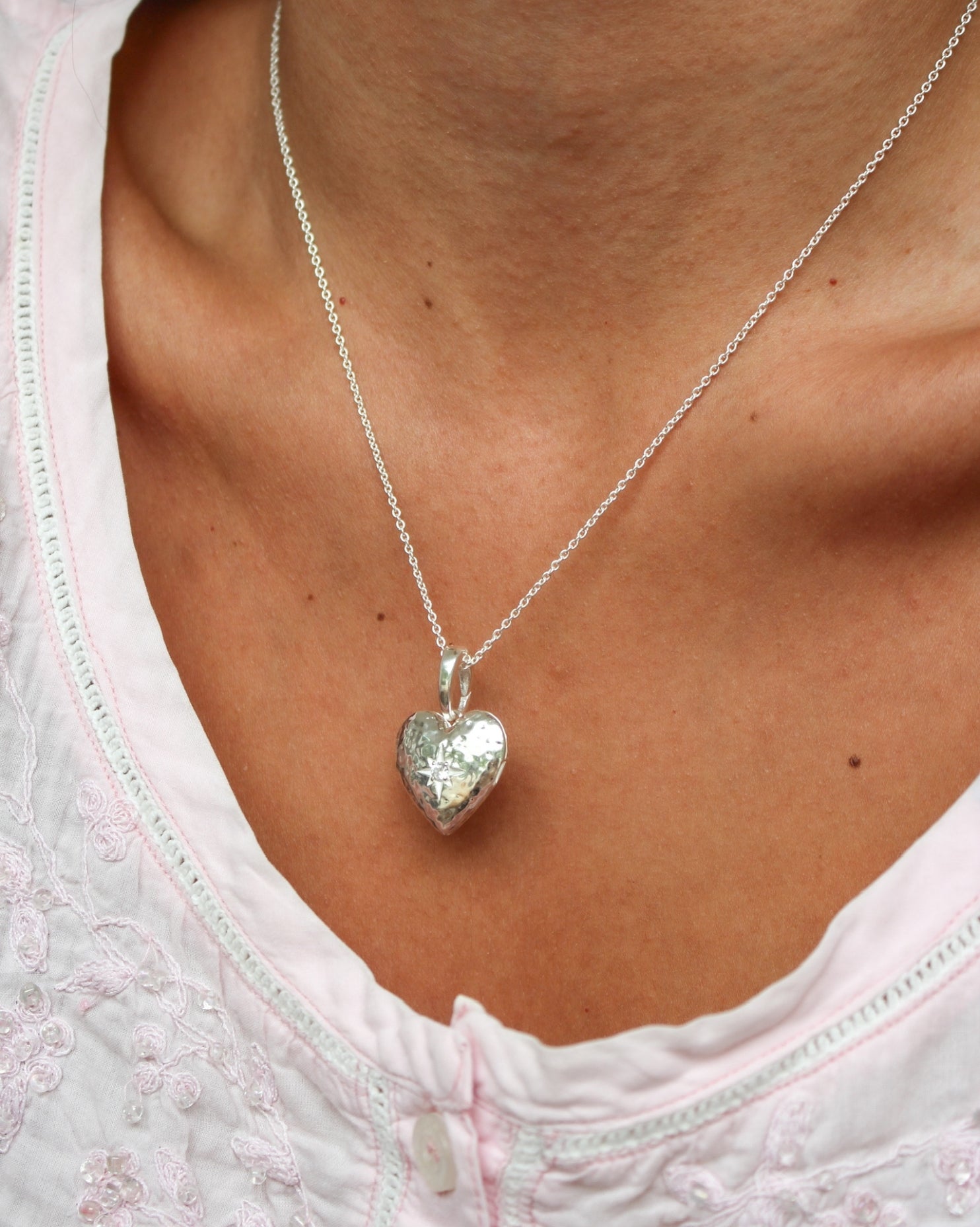 Silver heart locket necklace worn on delicate chain