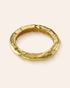 Gold bangle with a textured design on a light beige background